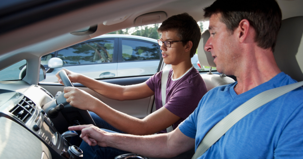 teenage boy driving with dad beside him
